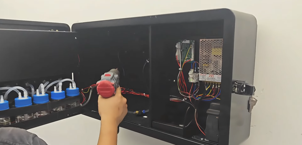 Wall-mounted perfume vending machine being installed with a technician using a drill